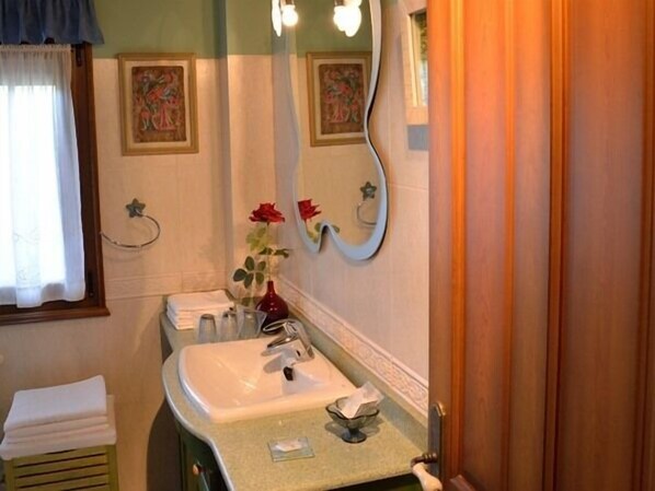 A bathroom with a sink, mirror, and two framed pictures on the wall. - Posada Bernabales (Liérganes)
