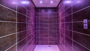 A modern bathroom with purple-tiled walls and a white floor.