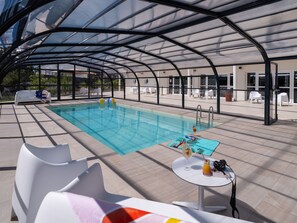 Uma área de piscina coberta com espreguiçadeiras e uma mesa com bebidas.