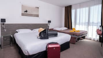 Quarto de hotel com duas camas, uma mala vermelha, uma bolsa preta e um brinquedo de polvo amarelo sobre uma das camas.