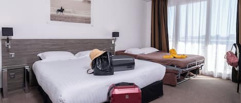 Habitación de hotel con dos camas, una maleta roja, un bolso negro y un juguete de pulpo amarillo sobre una de las camas.