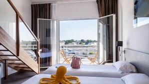 A hotel room with two beds, a large window with curtains, a view of the city, and a wooden staircase.