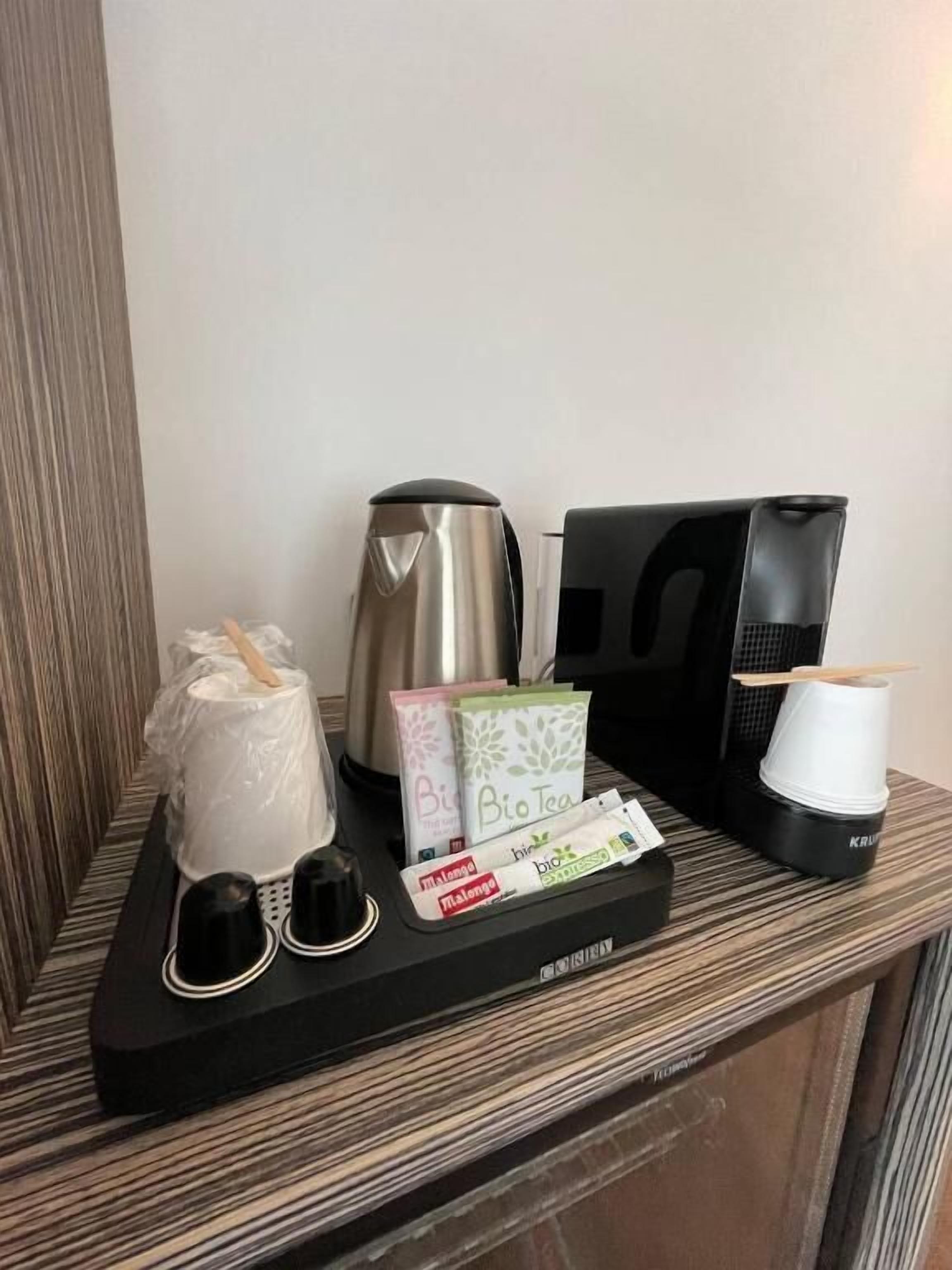 A coffee station with a coffee maker, cups, and coffee pods.