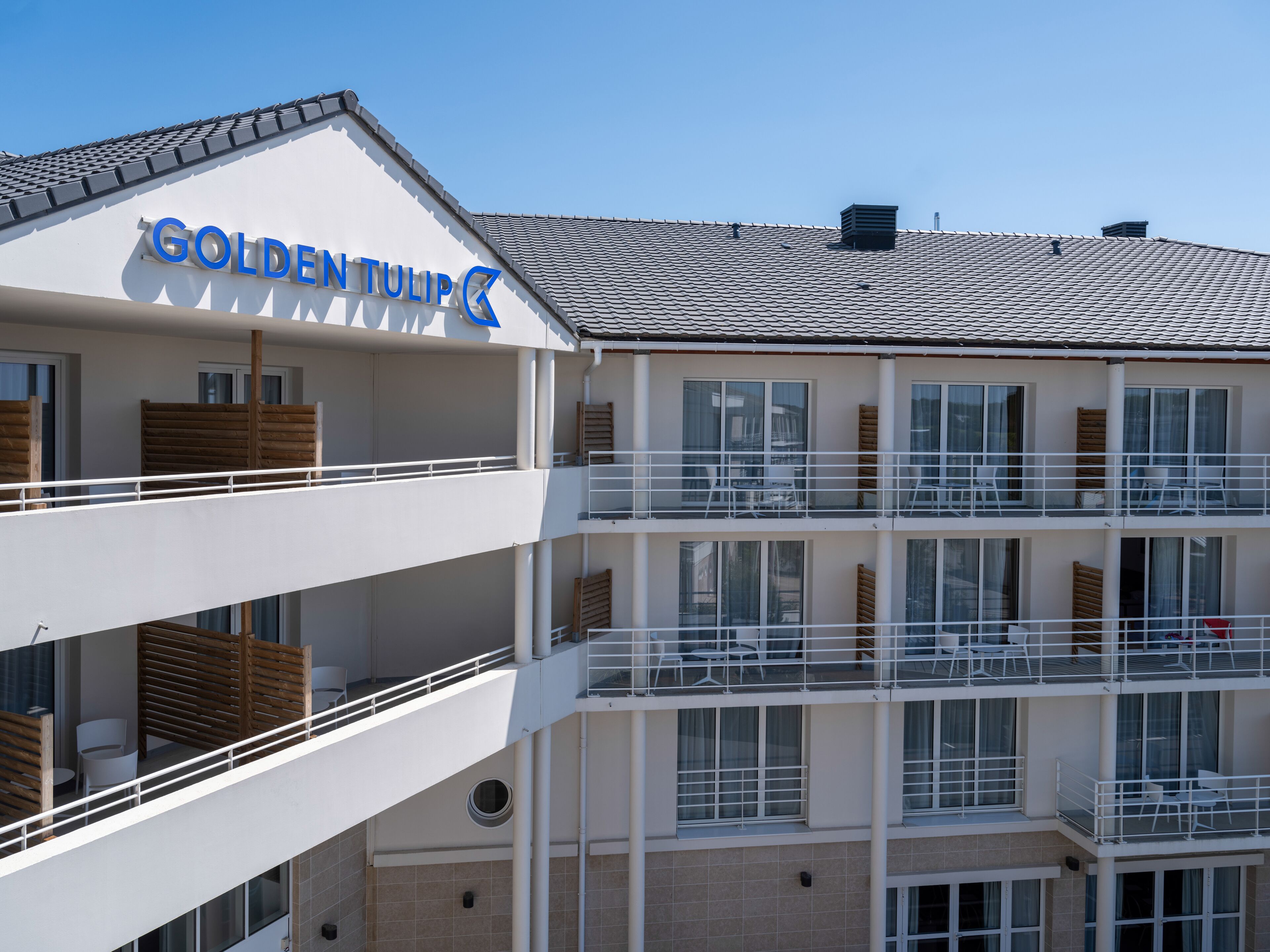 A multi-story hotel with balconies, large windows, and a sign reading "GOLDENTULIP".