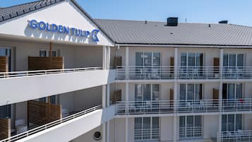 Um hotel com vários andares, varandas, janelas amplas e uma placa com a inscrição 'GOLDENTULIP'.