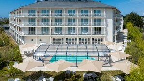 A multi-story hotel with a swimming pool and outdoor seating area. - Golden Tulip La Baule Hôtel & Résidence (La Baule-Escoublac)