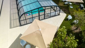 A glass-enclosed swimming pool with lounge chairs and umbrellas.