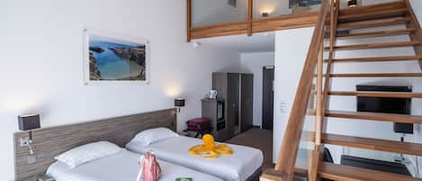 A hotel room with two beds, a wooden staircase, a desk, and a TV.