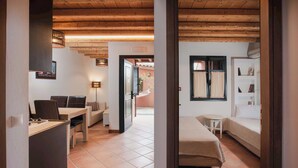 Una habitación con techo de madera, un escritorio con silla, una cama con cabecera y una pequeña mesa con silla.