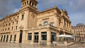 Un edificio histórico con detalles arquitectónicos ornamentales, que incluyen una torre destacada y múltiples ventanas.