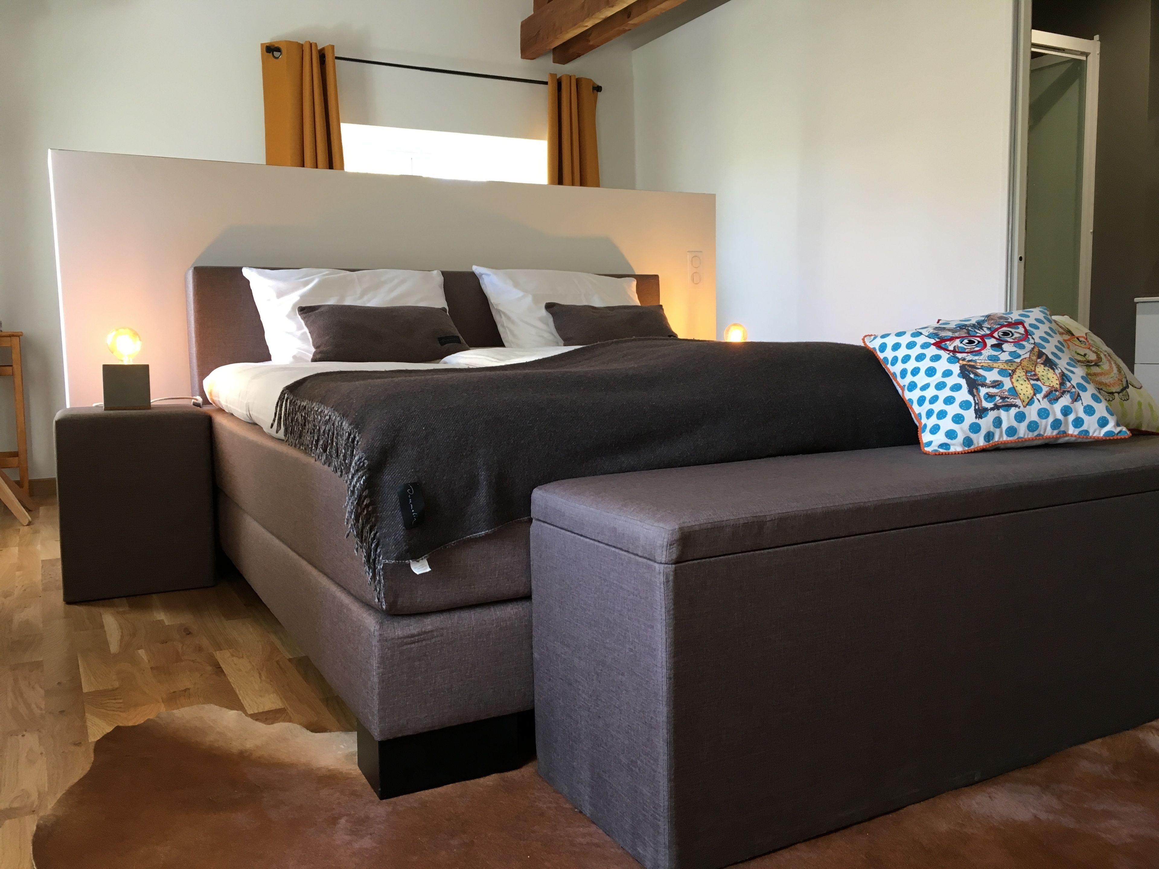 Een moderne slaapkamer met een bed, nachtkastjes en een bank.