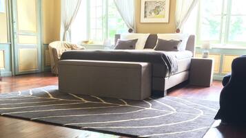 A bedroom with a bed, a nightstand, a chair, a rug, and a window with curtains.