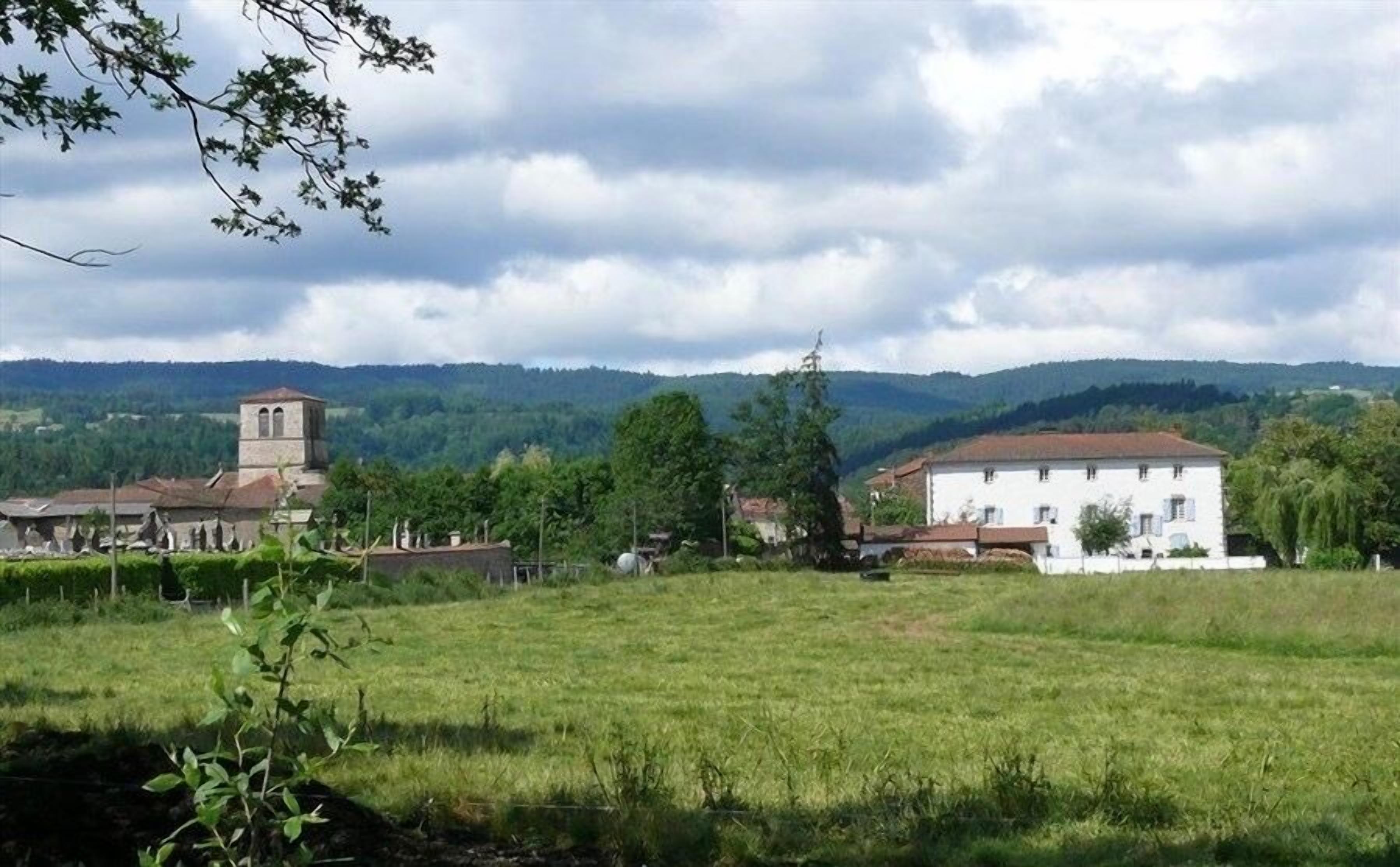 Paisatge rural amb una església, un edifici blanc i un camp.