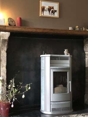 Una chimenea de diseño moderno, un cuadro enmarcado encima y una planta en maceta a un lado.
