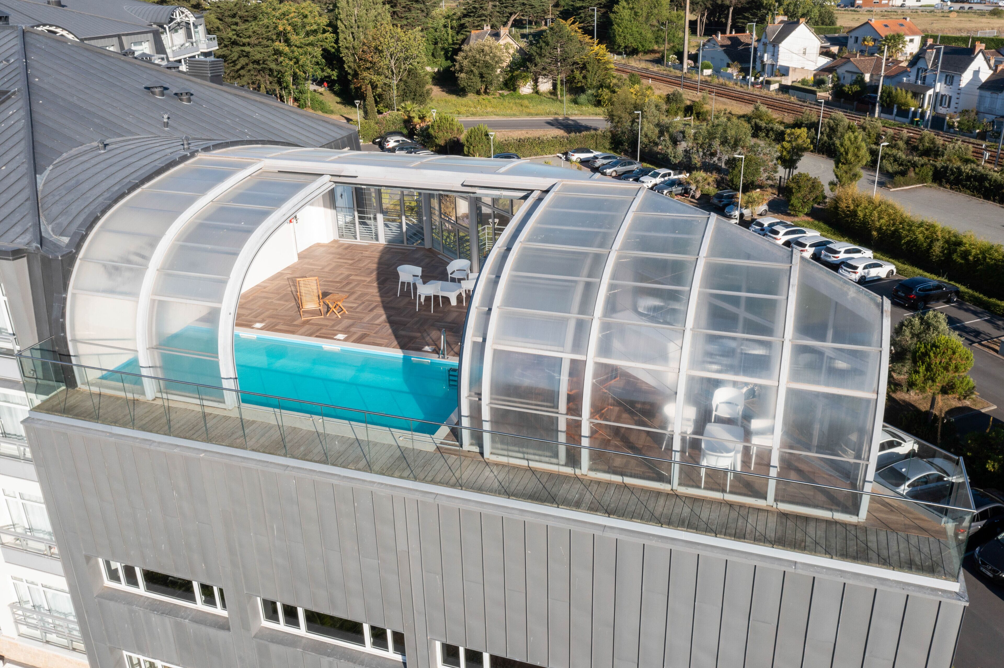 Un bâtiment moderne doté d’une piscine couverte, dont la structure est entièrement faite de verre, située sur le toit.