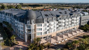A multi-story hotel with a curved roof, balconies, and a pool area with umbrellas. - Westotel Le Pouliguen (Le Pouliguen)