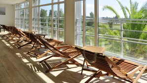 A sunlit room with large windows, wooden lounge chairs, and a table. - Westotel Le Pouliguen (Le Pouliguen)