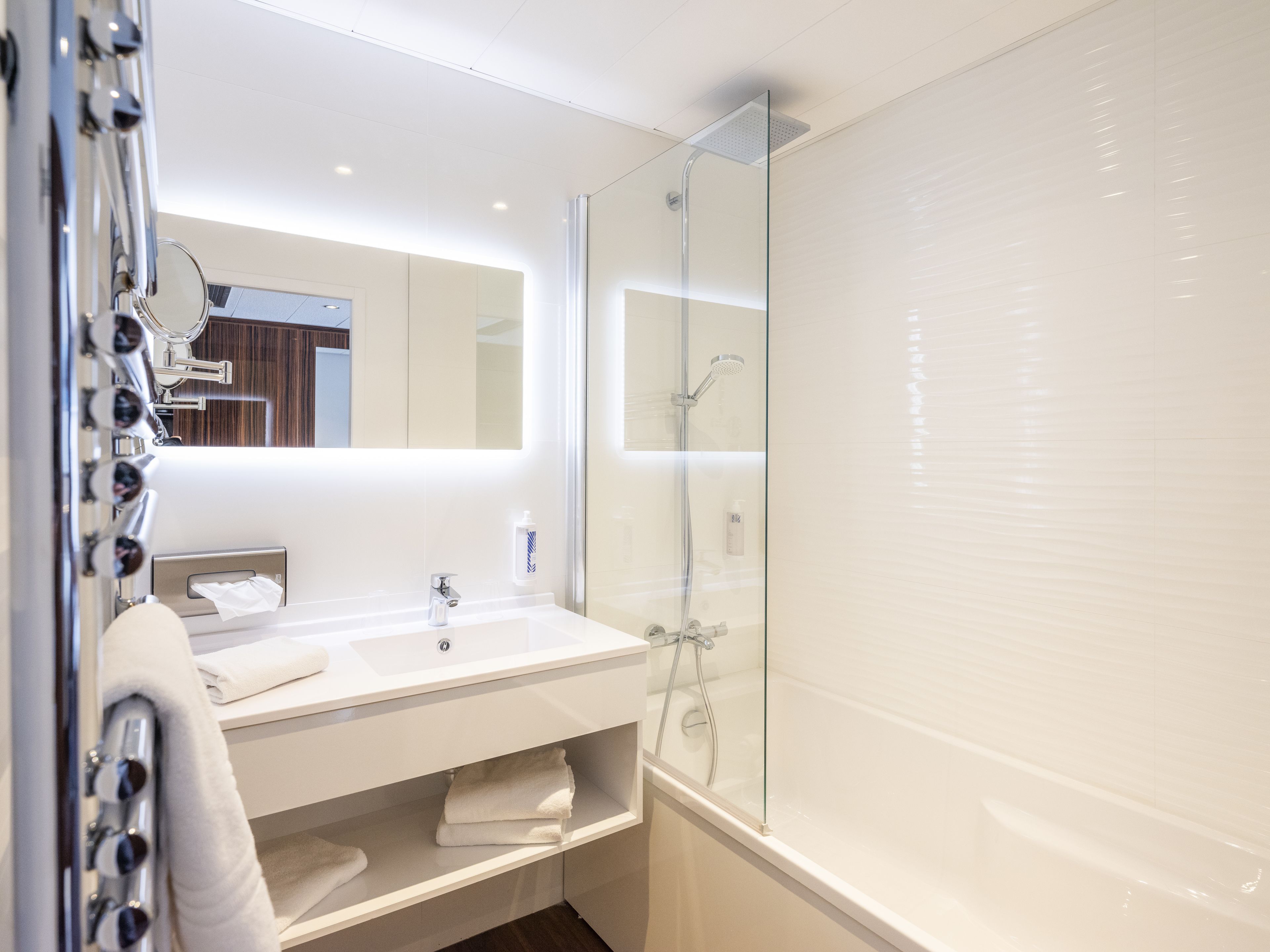 A modern bathroom with a glass-enclosed shower, a white sink, and a mirror above the vanity.