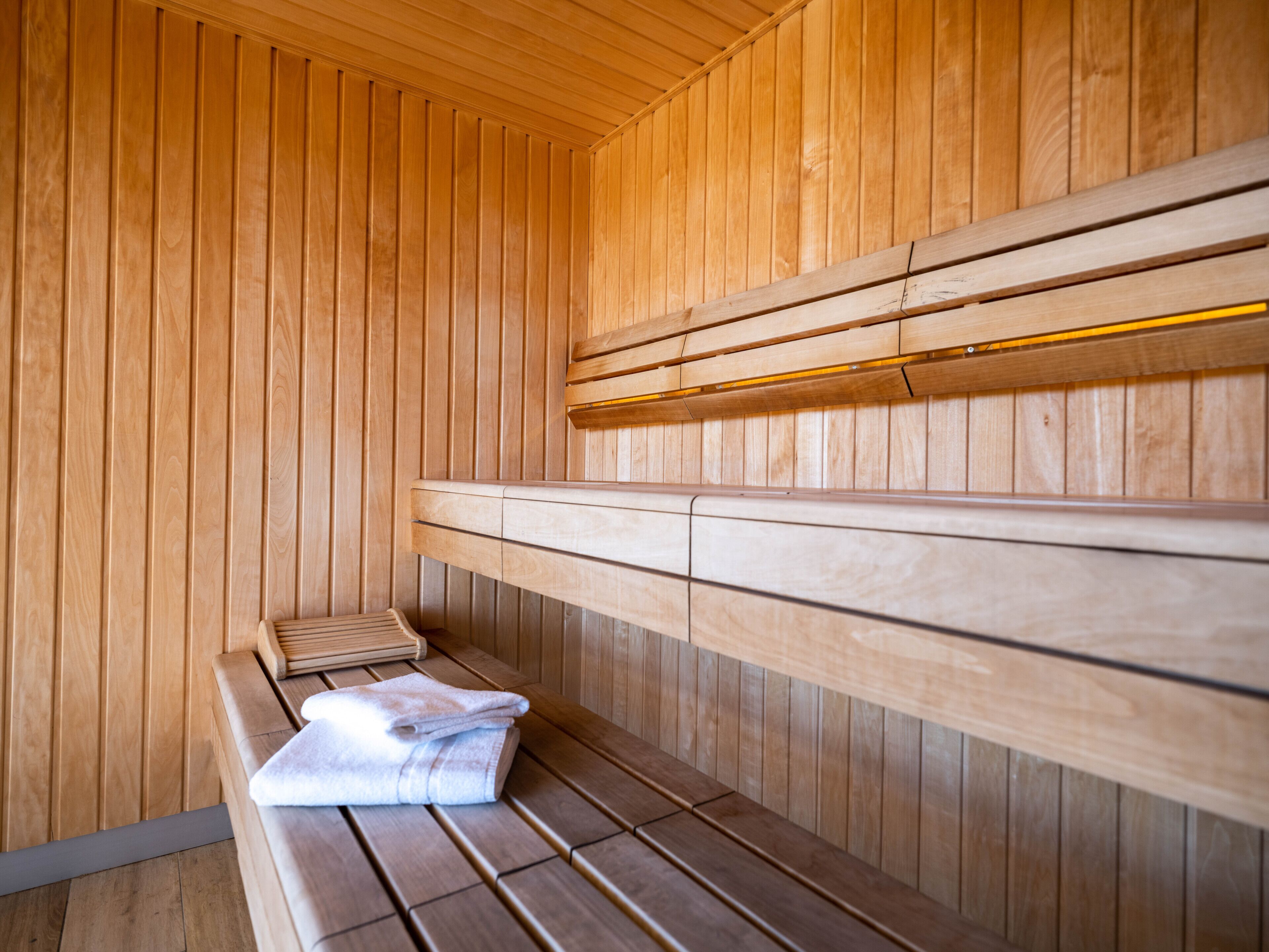A sauna with wooden benches and a bench with a towel.