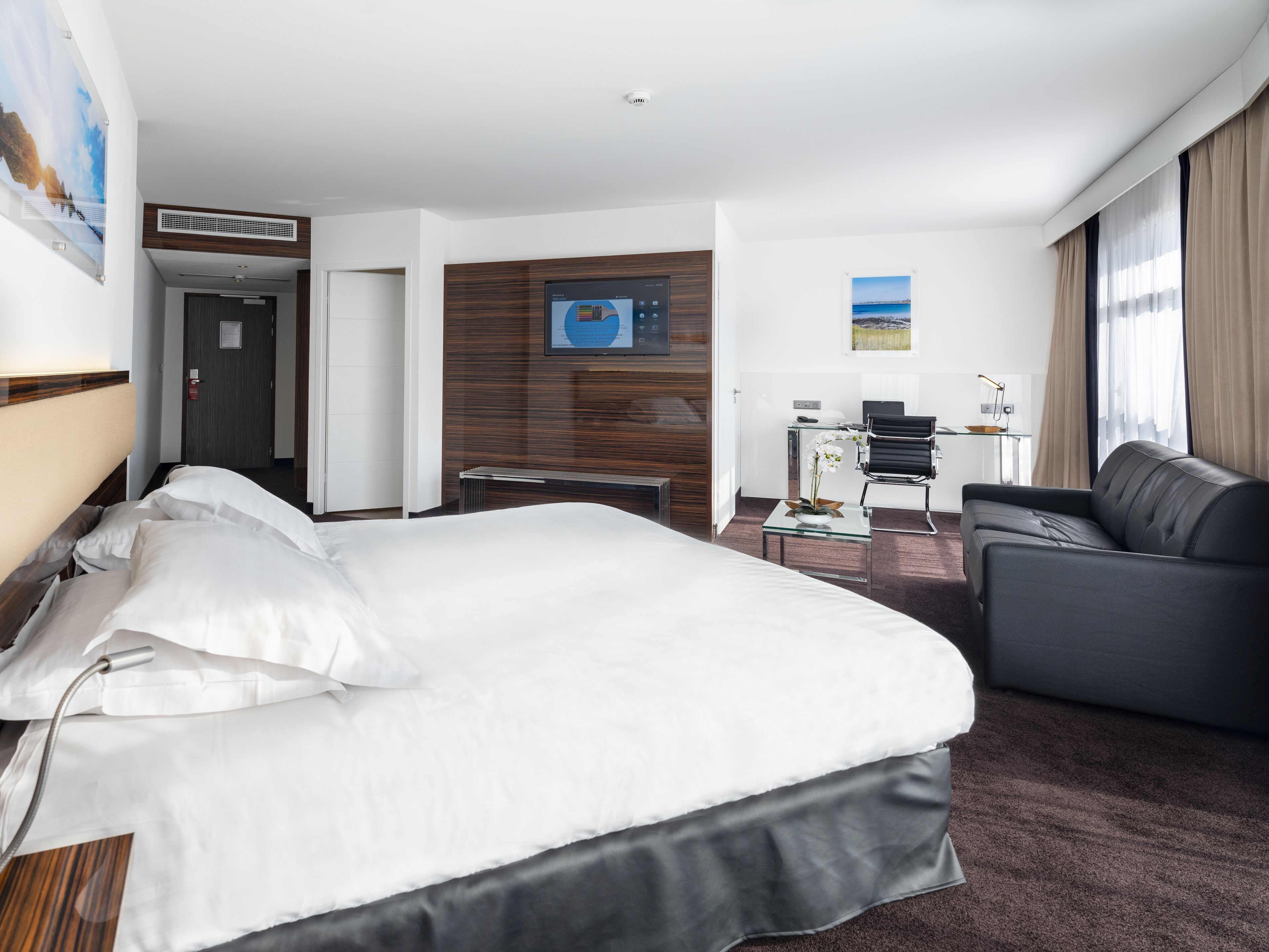 Une chambre d’hôtel avec un grand lit, un canapé, un bureau et une chaise.