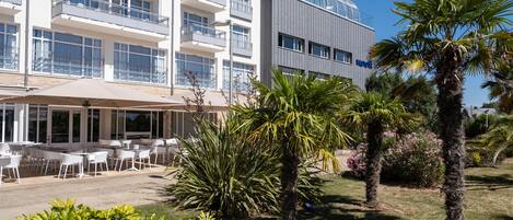Un hotel moderno con asientos al aire libre y palmeras.
