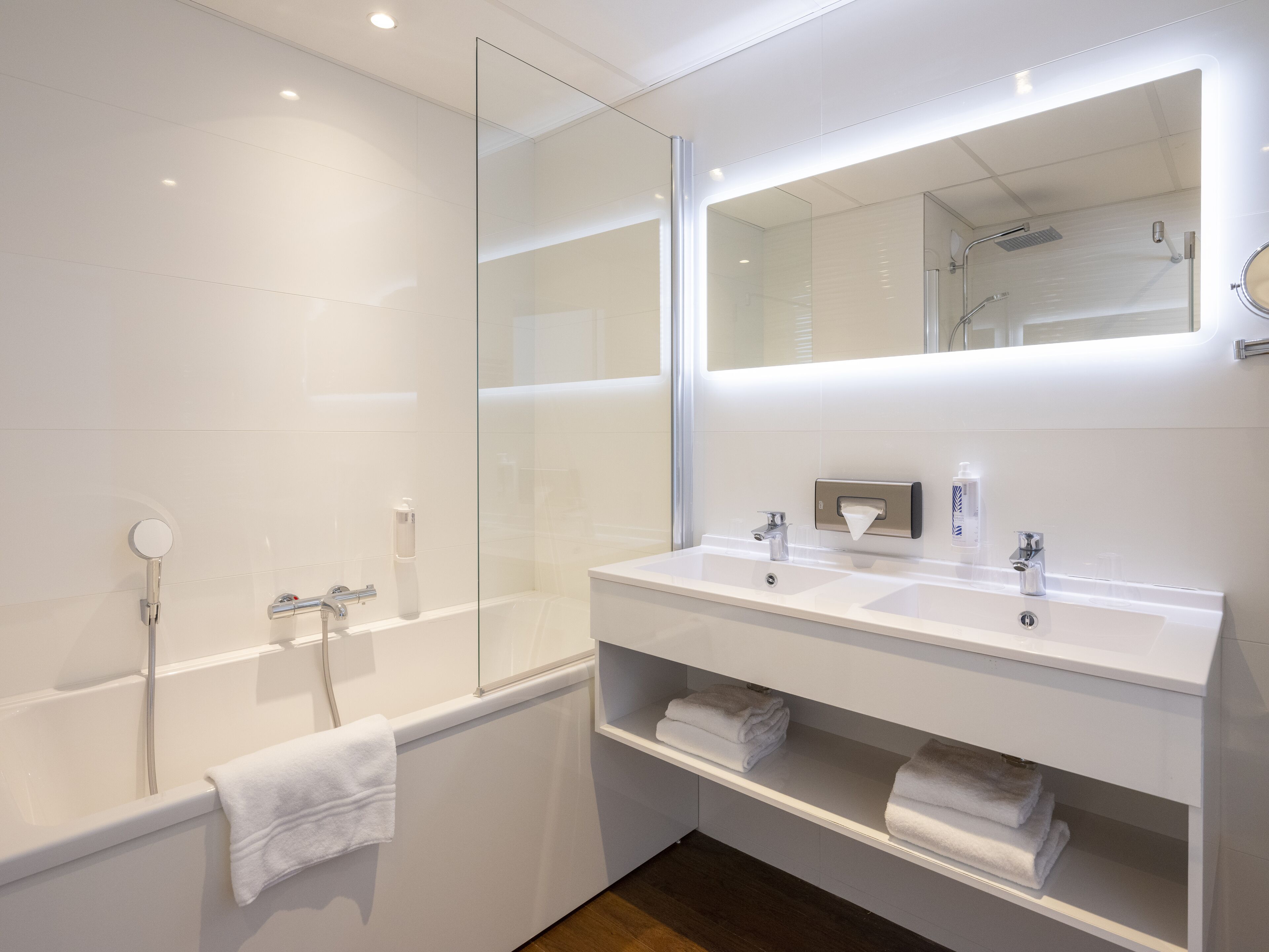 A modern bathroom with a glass-enclosed shower, two sinks, and a large mirror.