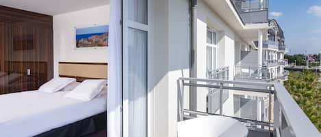 Ein Hotelzimmer mit Bett, einer Schiebetür zum Balkon und Meerblick.