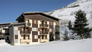 Un hotel de varios pisos con balcones, ubicado en una zona montañosa nevada.