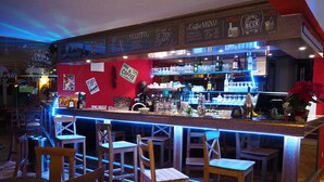 Zona de bar con taburetes y barra, mostrando un menú de café y diferentes opciones de bebidas.
