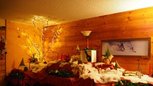 Una mesa festiva con decoraciones navideñas, incluyendo luces, un pequeño árbol y una botella de vino.