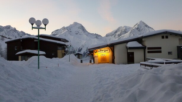 Un pueblo en la montaña cubierto de nieve con un restaurante Sherpa.