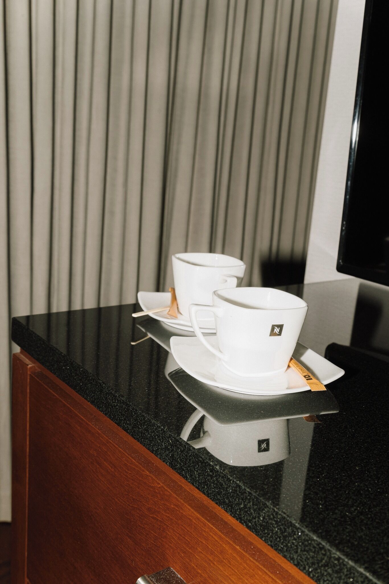 A coffee maker with a cup and saucer on a black countertop.
