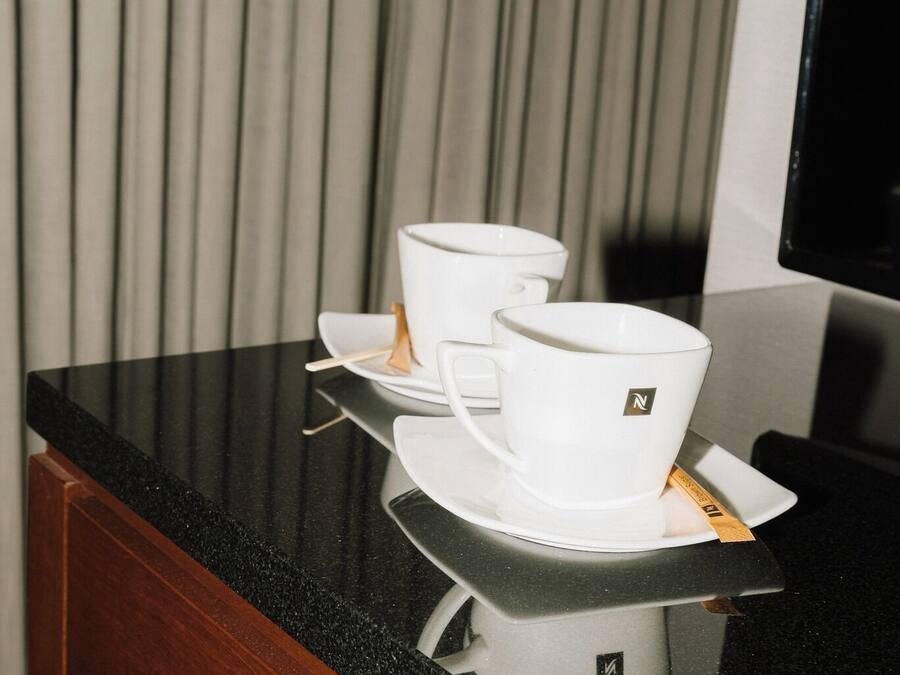 A coffee maker with a cup and saucer on a black countertop.
