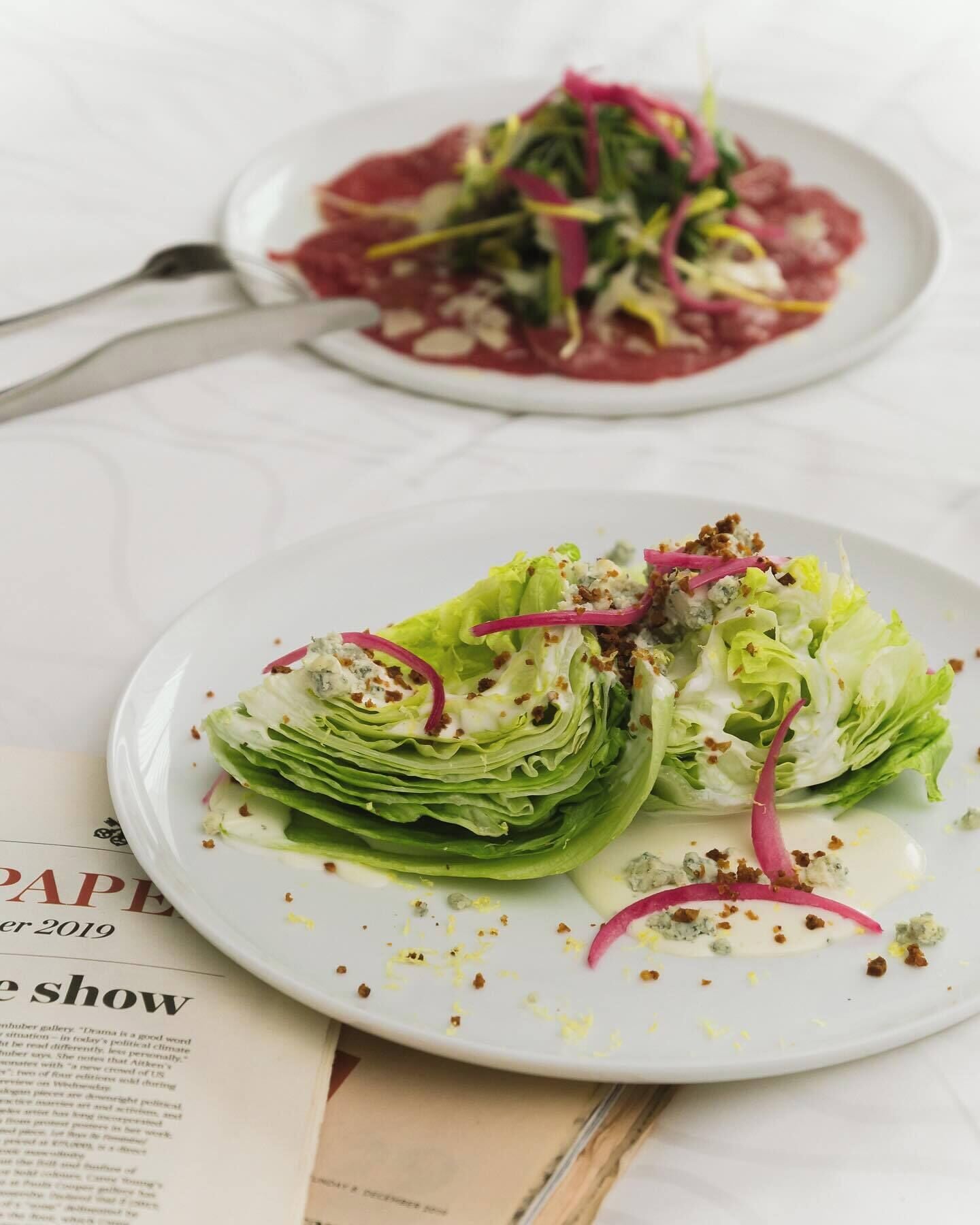 A plate of food with lettuce and blue cheese garnished with red onion and crumbled bacon.