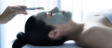 A person lying down with a facial mask being applied.