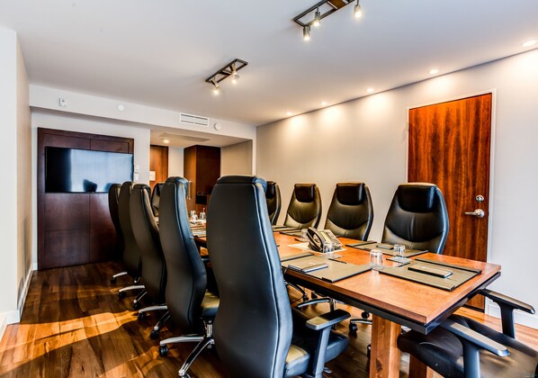 A conference room with a long table, multiple chairs, and a television on the wall.