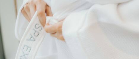 A person wearing a white robe with the text "SPA EXPERIENCE" on it.