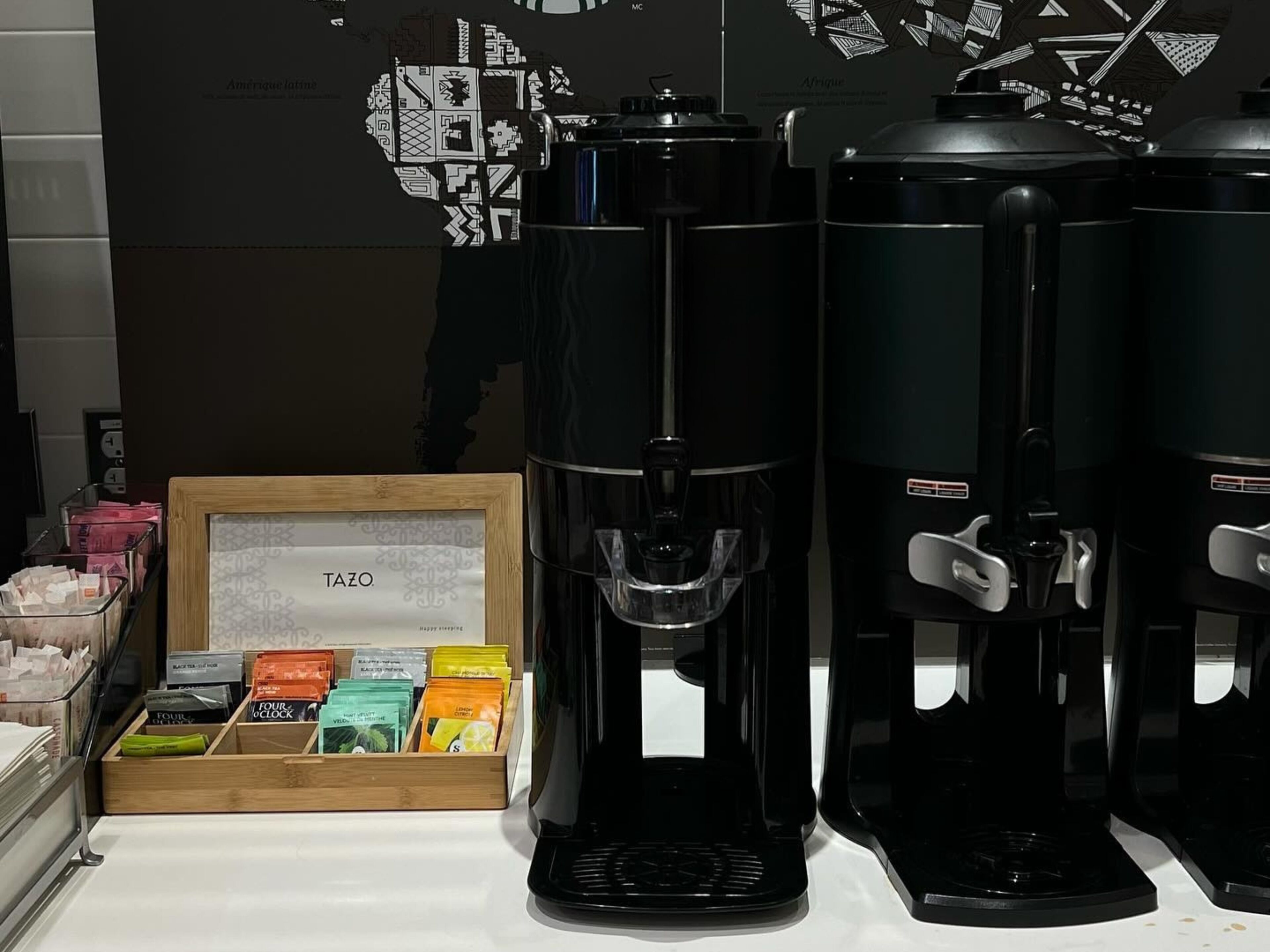 A coffee station with two coffee makers and a display of coffee pods.