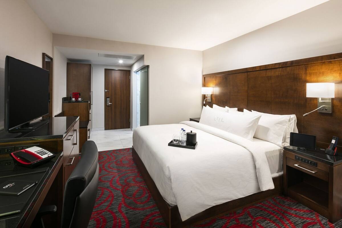 Ein Hotelzimmer mit Bett, Schreibtisch, Fernseher und einer Badezimmertür.