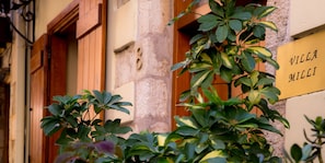 Ένα κτίριο με μια πινακίδα που γράφει «Villa Milia» και έναν πέτρινο τοίχο με τον αριθμό «8» πάνω από μια πόρτα.