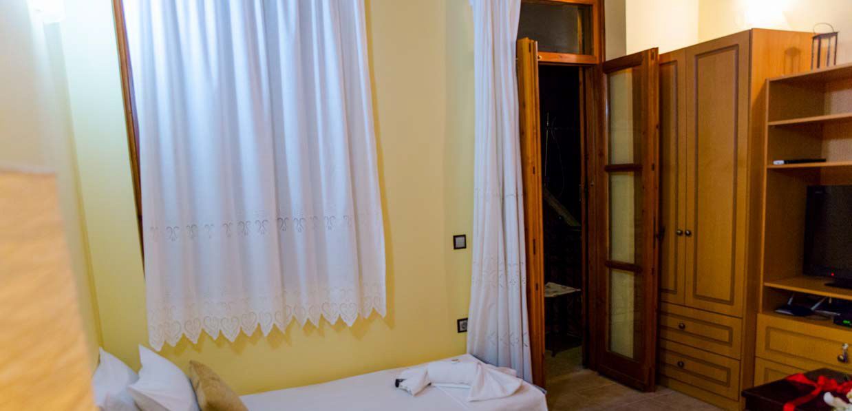 Un dormitorio con cama, armario y televisor.