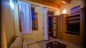 A cozy living room with a sofa, a coffee table, wooden cabinets, and a TV. - Villa Milli (Chania)