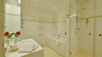 A modern bathroom with a large mirror, a bathtub, a shower, and a sink.