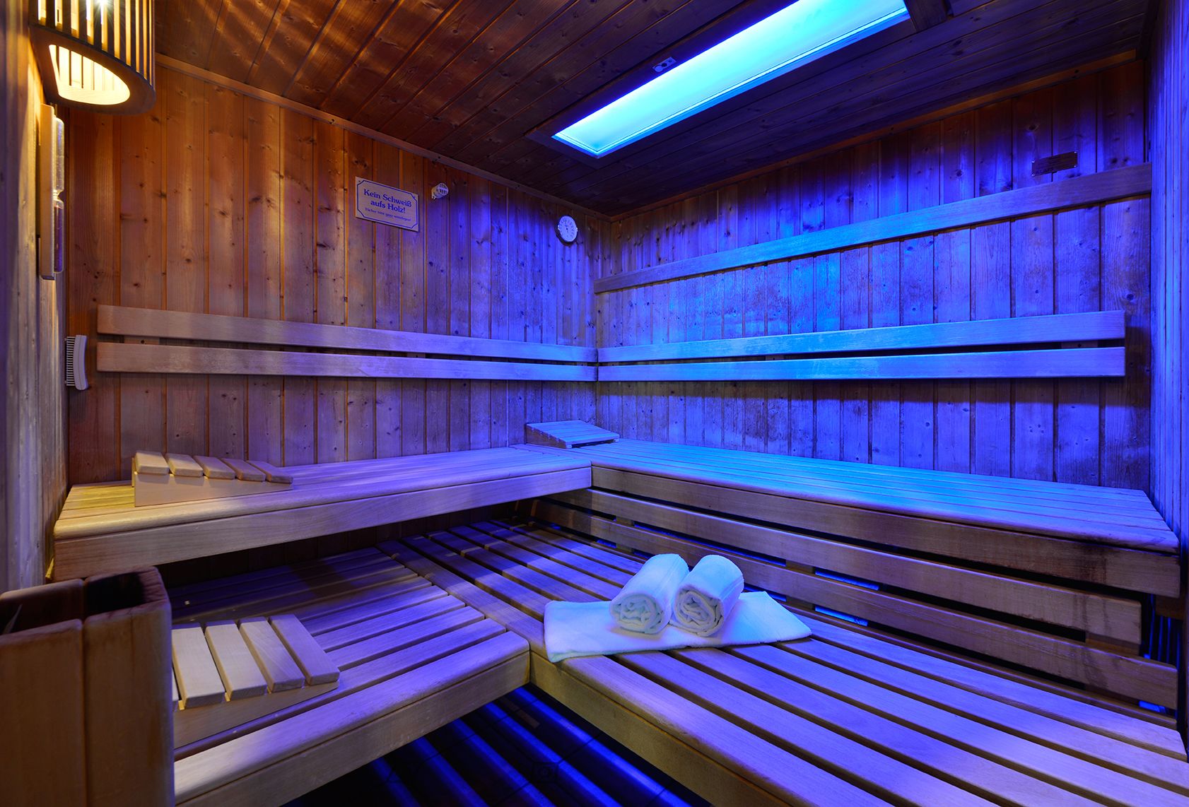 A wooden sauna with benches and benches, a heater, and a towel on the floor.