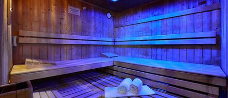 A wooden sauna with benches and benches, a heater, and a towel on the floor.