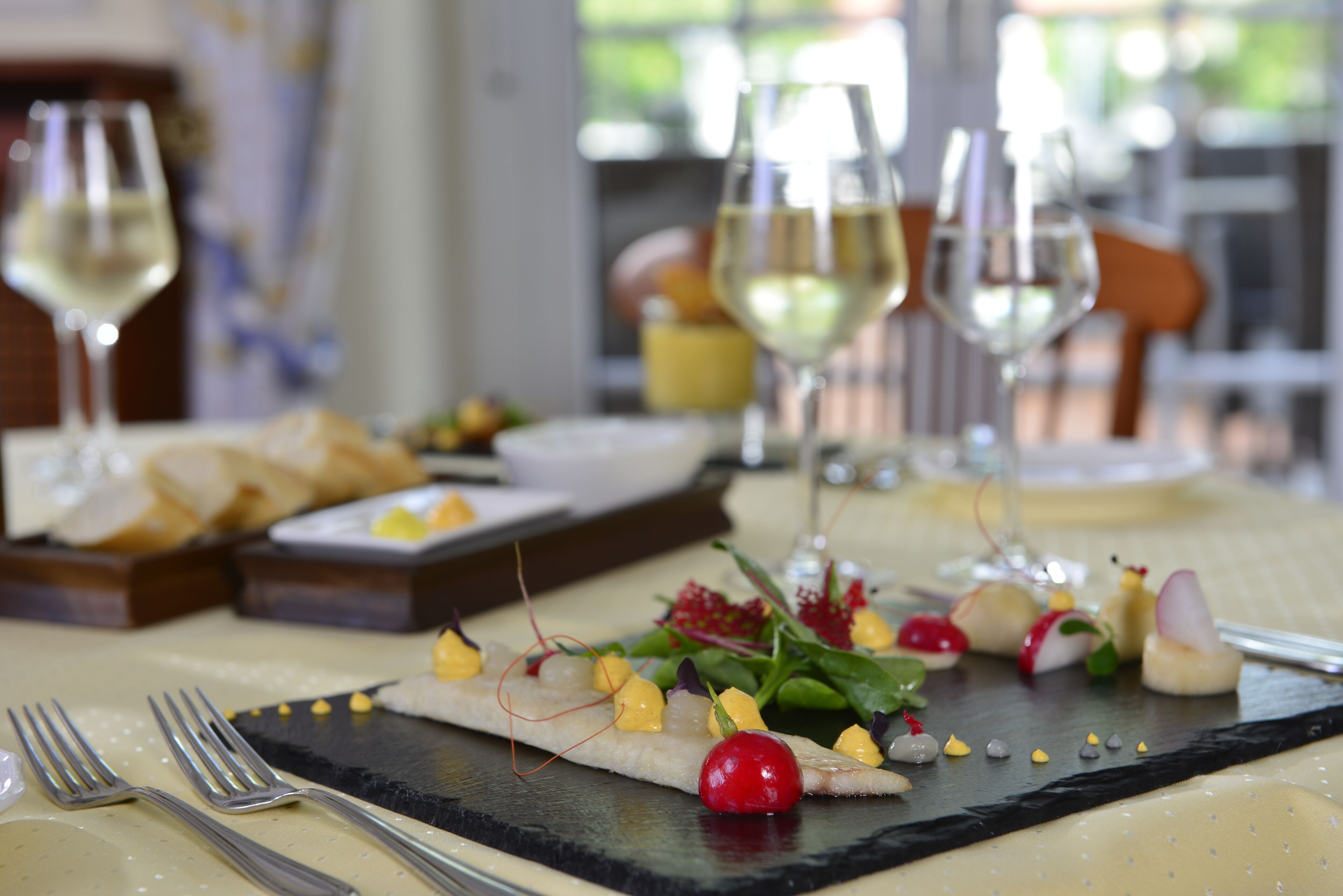 Una mesa de comedor con una variedad de platillos, incluyendo una tabla de embutidos y un plato de pizarra con aperitivos.