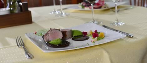 A dining table with a plate of food, wine glasses, and cutlery.