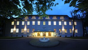 A large, multi-story building with a central entrance and a circular fountain in front. - Hotel Der Lindenhof (Gotha)