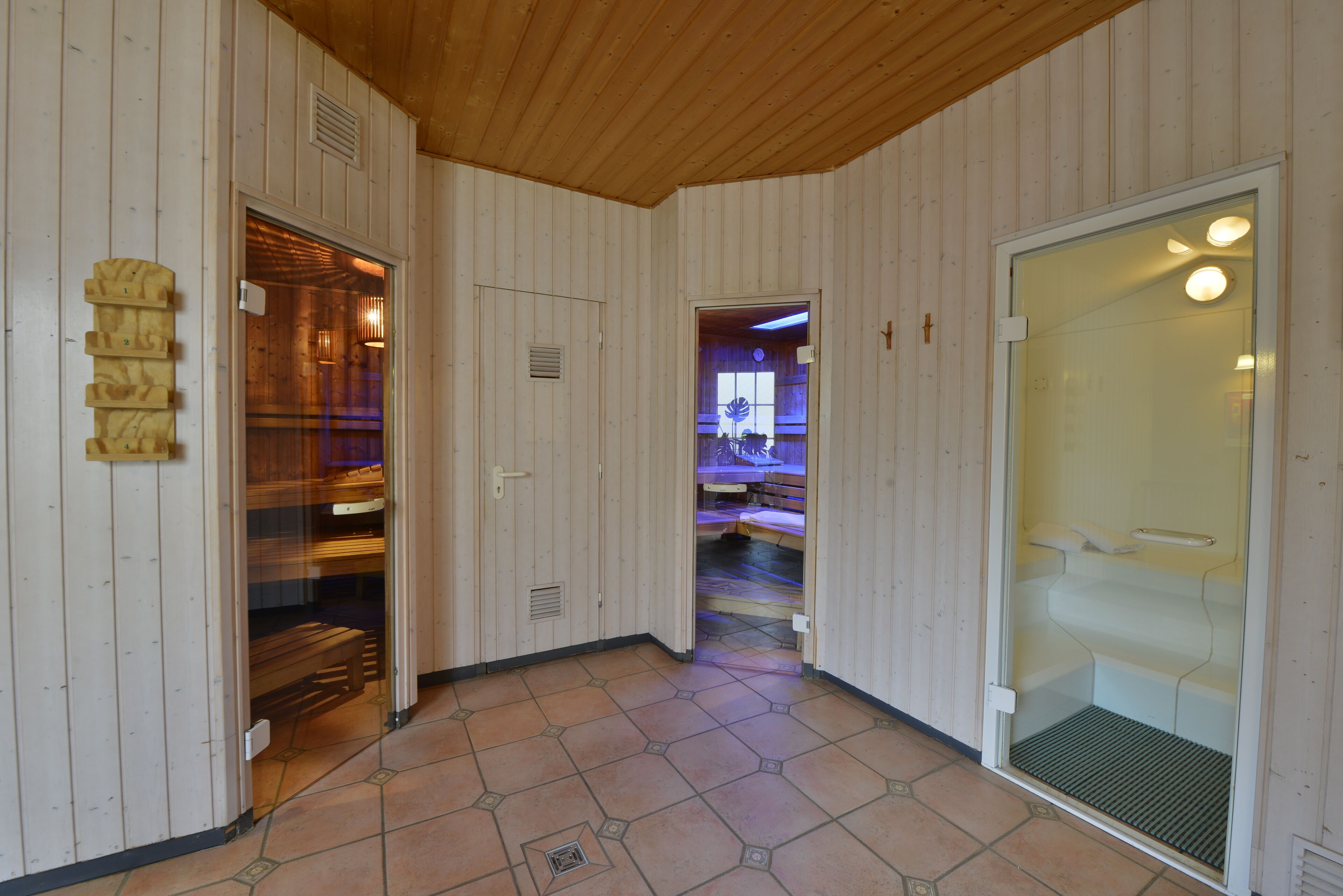 Un pasillo con paredes de madera y suelo de baldosas, que conduce a una habitación con cama y baño.