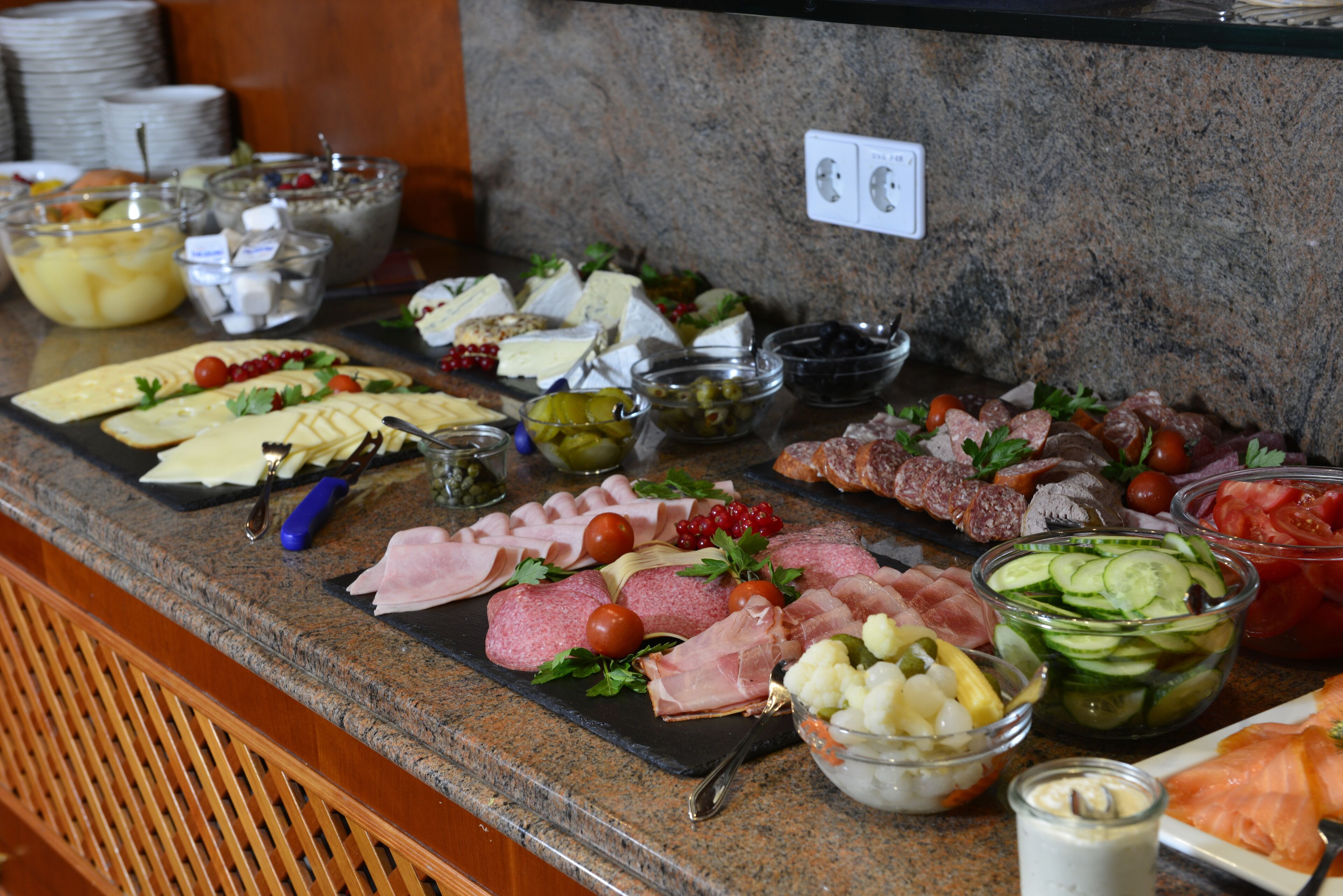 A buffet with various food items including meats, cheeses, and fruits.